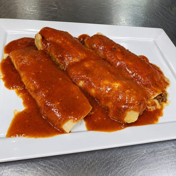 Three enchiladas covered in rich red sauce, served on a white rectangular plate.