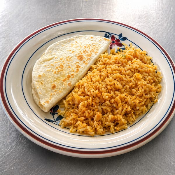 A plate of Mexican rice and a folded flour tortilla on a white plate with blue and red stripes.