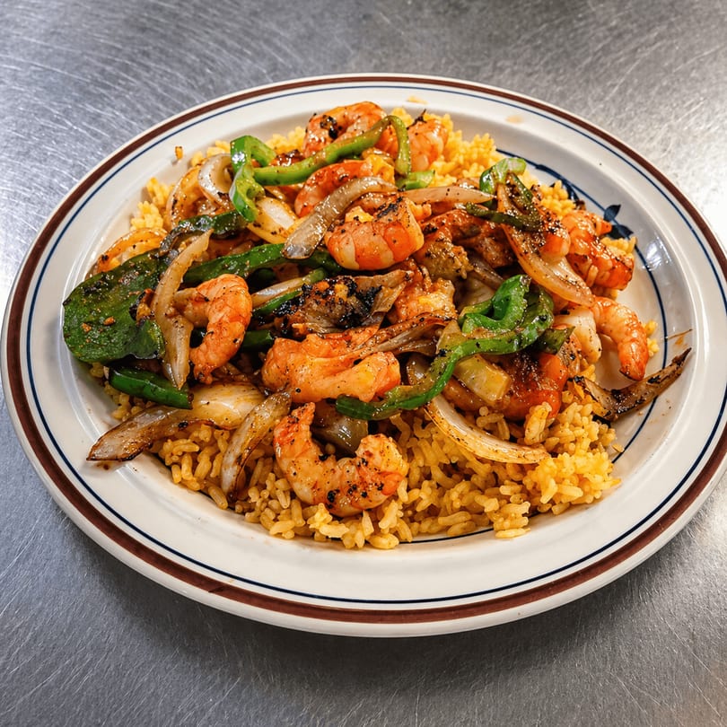 A plate of shrimp fajitas with grilled onions, green peppers, and yellow rice.